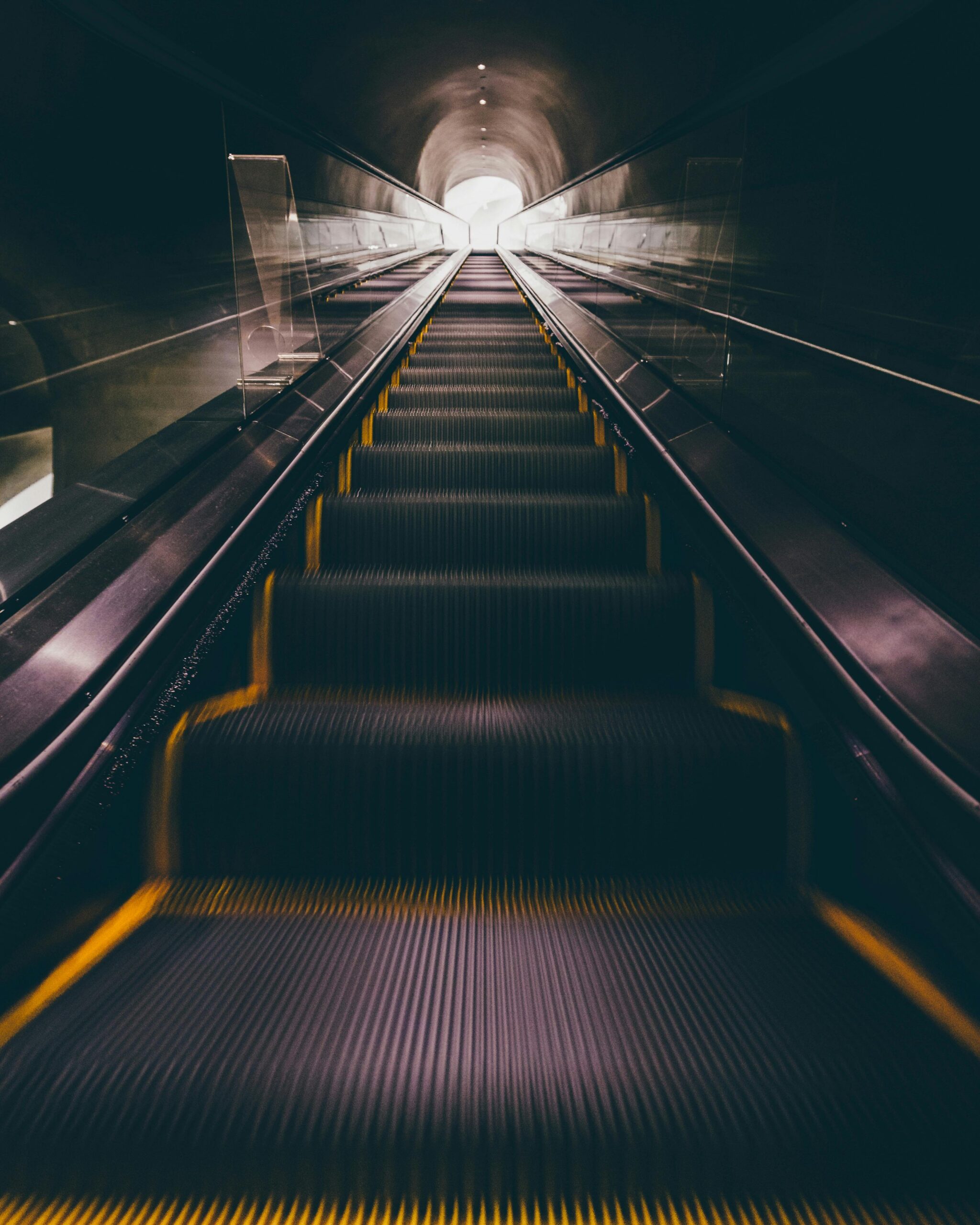 A captivating view of a modern escalator leading upwards in a dimly lit indoor tunnel.